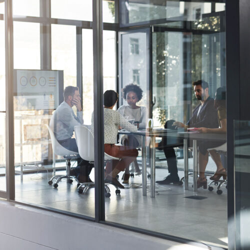 Business professionals meeting in a glass conference room to discuss SOW and workforce solutions